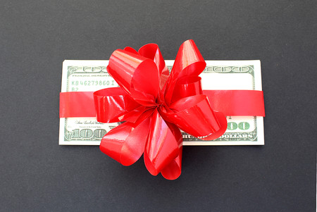 money dollars wrapped in a bow on a giftの写真素材