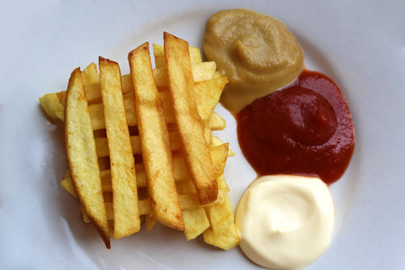 French fries on a plate with three kinds of sauce