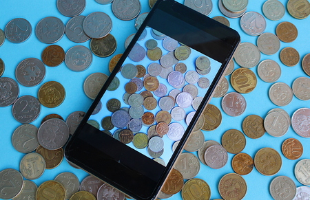 coins are scattered on the table and there is a telephone on themの写真素材