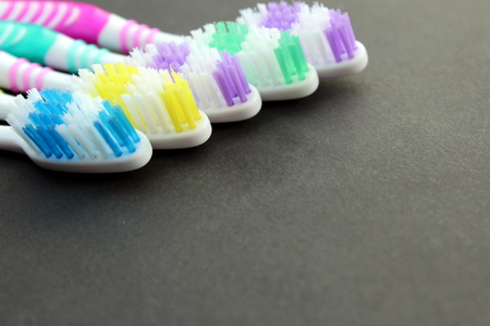 Multi-colored toothbrushes lie on a black backgroundの写真素材