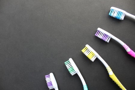 Multi-colored toothbrushes lie on a black backgroundの写真素材