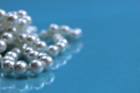 White pearl necklace lying on a blue backgroundの写真素材