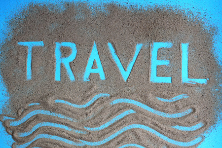 The word travel is written on the sandの写真素材