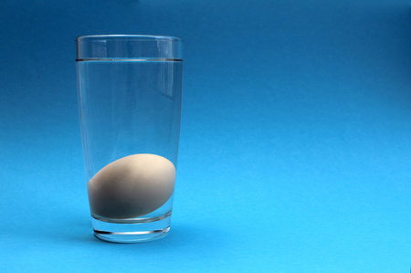 White chicken egg in a glass of water