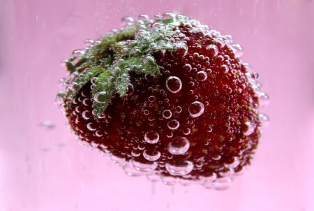 Ripe red strawberries in water covered with bubblesの写真素材