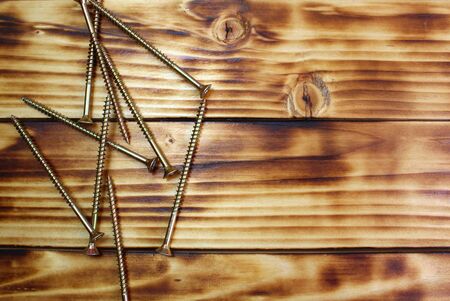 Iron long screws lie in one pile on a wooden tableの写真素材