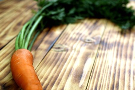 Fresh crop of carrots with bot lies on a wooden tableの写真素材