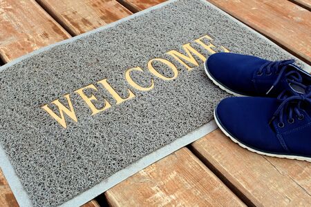 Welcome is written on the rug and shoes are standing nearbyの写真素材