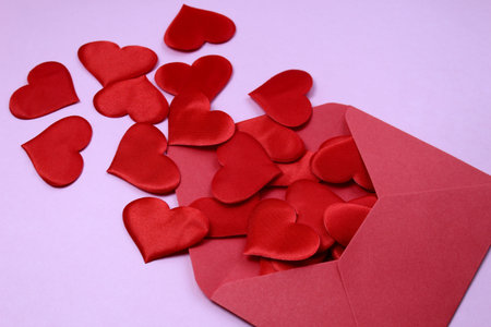 red hearts showered from an envelope on a pink background