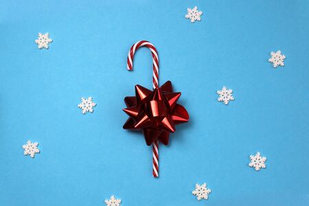 on a blue background lies a candy cane with a bowの写真素材
