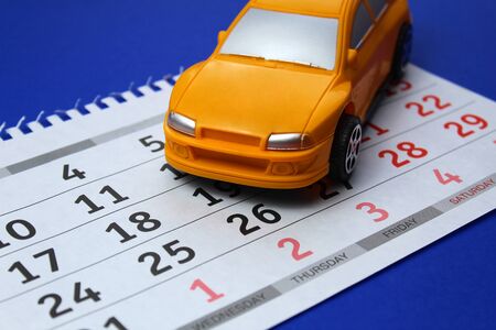 Yellow toy car on a calendar backgroundの写真素材