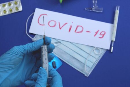 Hands in blue gloves hold a syringe and ampouleの写真素材