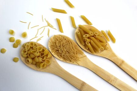 Three types of pasta in wooden spoons on a white backgroundの写真素材