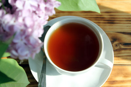 Still life, a bouquet of lilacs with a cup of tea in the early morning