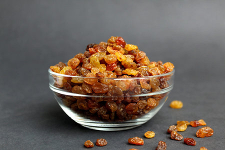 Raisins in a glass transparent bowl on a black backgroundの写真素材