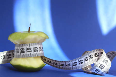 Stub of a green apple with a centimeter tape on a blue backgroundの写真素材