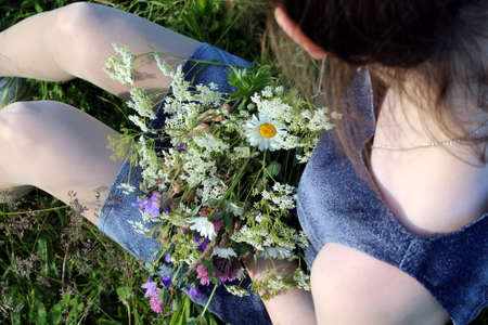 Girl holding wildflowers in her hands, top viewの写真素材