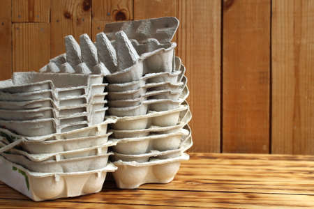 Empty egg containers lie stacked on wooden backgroundの写真素材