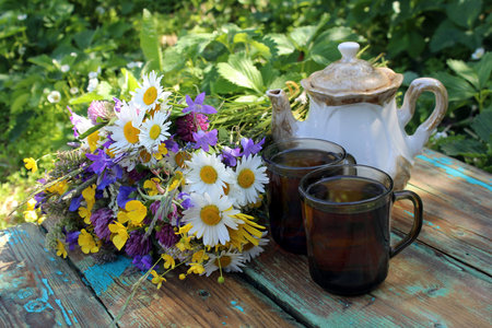 Still life, on the table there is a vase with wildflowers, with cups of tea and sliced cakeの写真素材