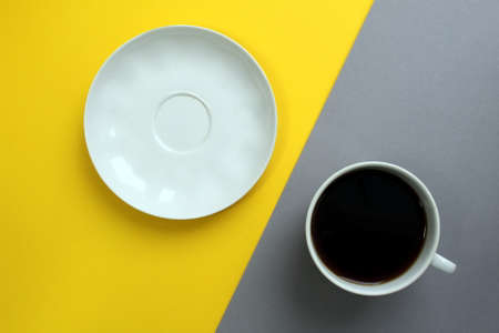 A cup of coffee stands on a yellow and gray bright backgroundの写真素材