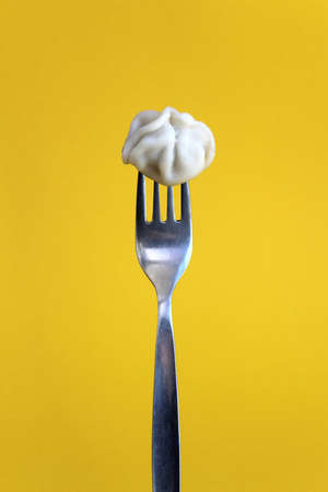 Delicious meat one dumpling impaled on a fork on a yellow backgroundの写真素材