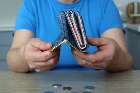 The girl shakes the last money out of her wallet on the tableの写真素材