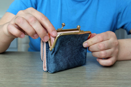 Female hands open a blue wallet standing on the table