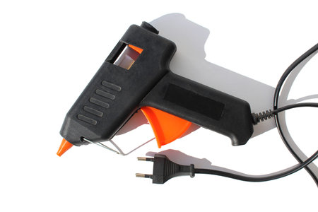A gun for liquid glue lies on a white background
