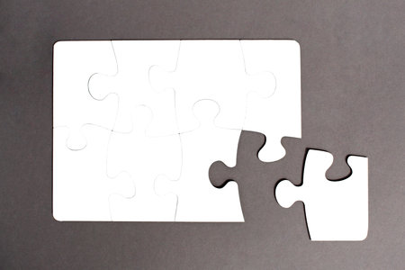 White jigsaw puzzles assembled on a gray background with a chipped piece