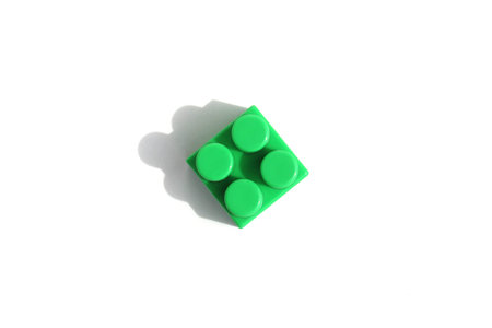 one green little brick, detail, on a white isolated background of their constructor set