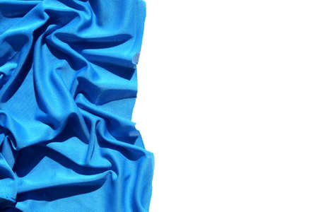 Blue fabric folds lies on a white isolated surface on a half photo with a place for textの写真素材