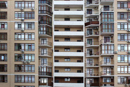 The texture of the facade of the house with windows and balconies with tables for relaxation.