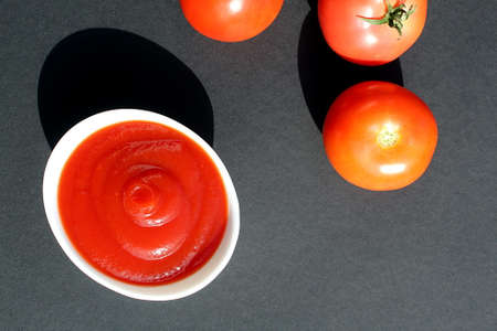 Tomato sauce lies in a white plate on a black background.の写真素材