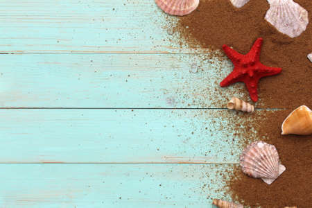 Red starfish with different seashells lies on a wooden background.の写真素材
