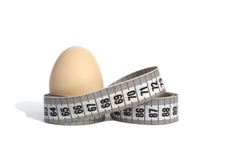 Chicken egg wrapped with a centimeter tape on a white isolated background.