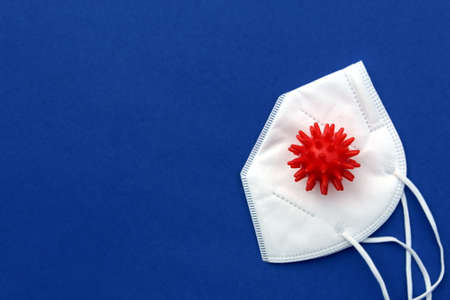 On a blue background lies a white mask with a mock-up of a virus.の写真素材