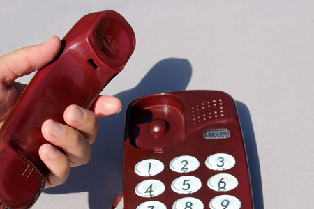 A woman`s hand holds a phone receiver in her hand to make a call.