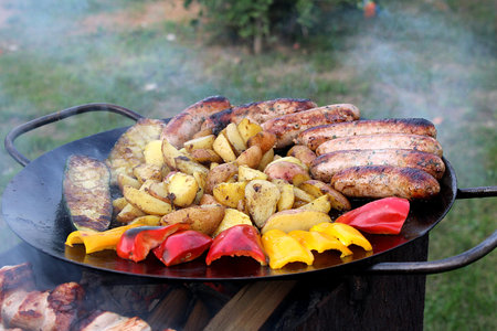 Fry meat with vegetables on the street. Delicious and unhealthy picnic food.