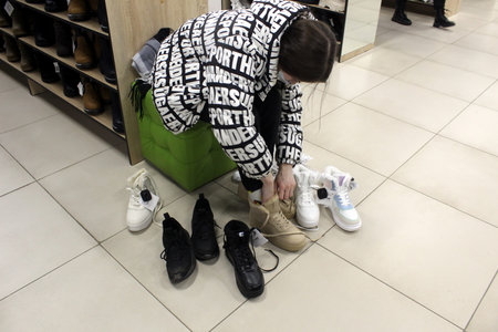 The girl sits and measures shoes in the store.の写真素材