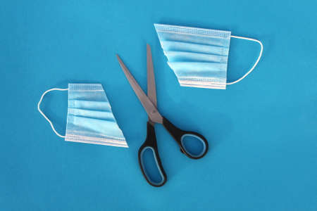 Medical mask cut in half with scissors on a blue background.の写真素材