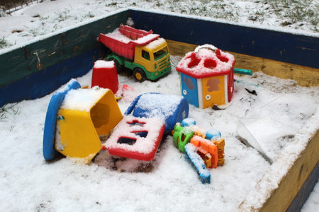 Children`s toys forgotten by children in the sandbox were covered with snow.の写真素材