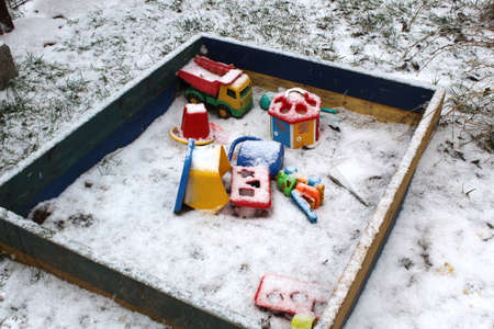 Children`s toys forgotten by children in the sandbox were covered with snow.の写真素材