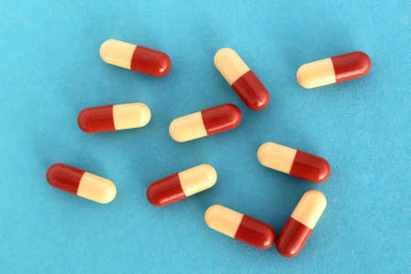 Medicine capsules lie in a heap on a blue background.の写真素材