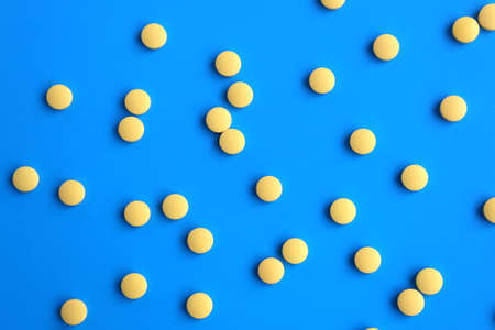 The texture of many yellow pills lie on a white background.の写真素材