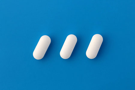 Three white oblong tablets lie on a blue background.の写真素材