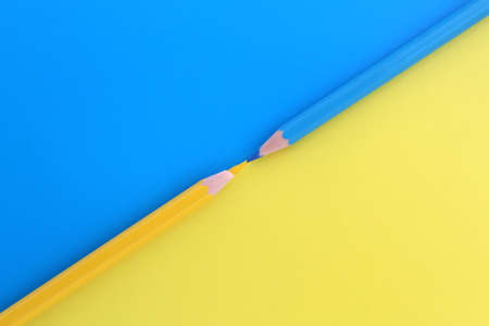 On a blue and yellow background, two pencils of the same color lie at the same time with space for text.の写真素材