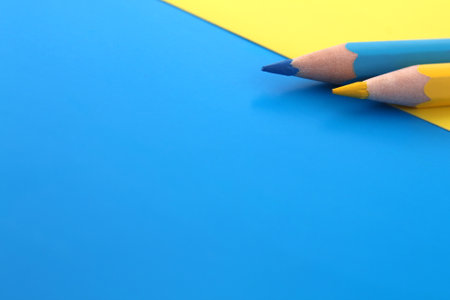 On a blue and yellow background, two pencils of the same color lie at the same time with space for text.の写真素材