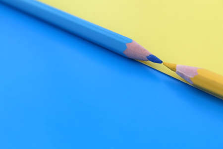 On a blue and yellow background, two pencils of the same color lie at the same time with space for text.の写真素材