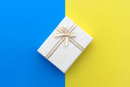 A white gift box stands on the border of yellow and blue.の写真素材