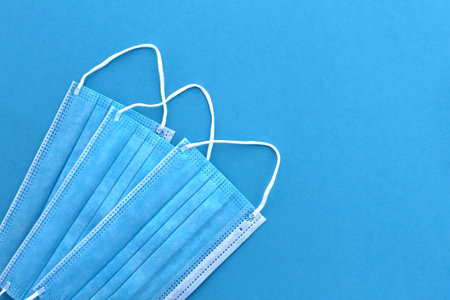 Three blue sterile medical masks lie on a blue background.の写真素材